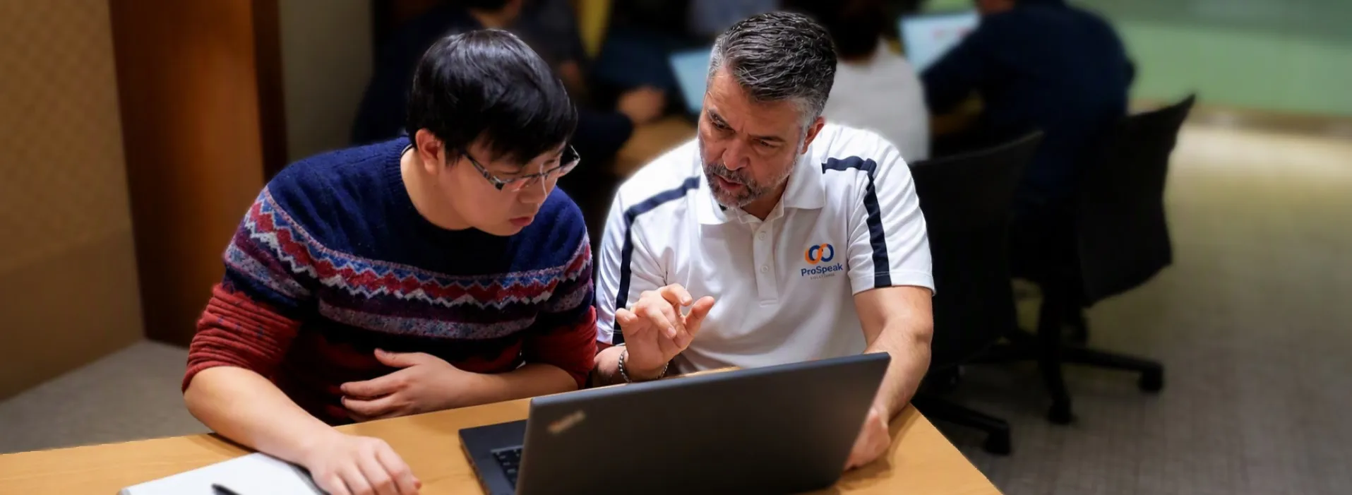 Trainer giving one-to-one feedback to a participant working on a laptop